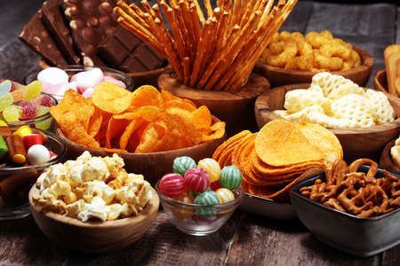 Salty snacks. Pretzels, chips, crackers in wooden bowls. Unhealthy products. food bad for figure, skin, heart and teeth. Assortment of fast carbohydrates food.の写真素材
