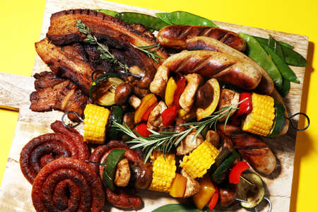 Assorted delicious grilled meat and skewer with vegetable and herbs on rustic tableの写真素材