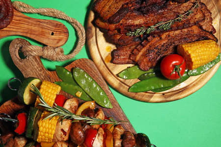 Assorted delicious grilled meat and skewer with vegetable and herbs on rustic tableの写真素材