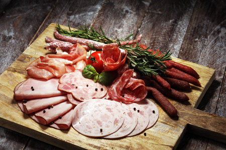 Food tray with delicious salami, pieces of sliced ham, sausage and salad. Meat platter with selection on tableの写真素材