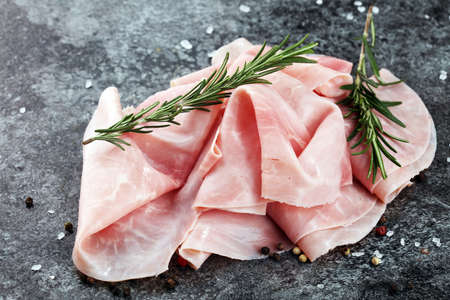 Sliced ham on wooden background. Fresh prosciutto. Pork ham sliced with rosemaryの写真素材