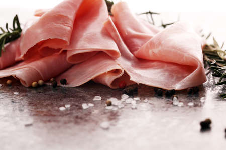 Sliced ham on wooden background. Fresh prosciutto. Pork ham sliced with rosemaryの写真素材