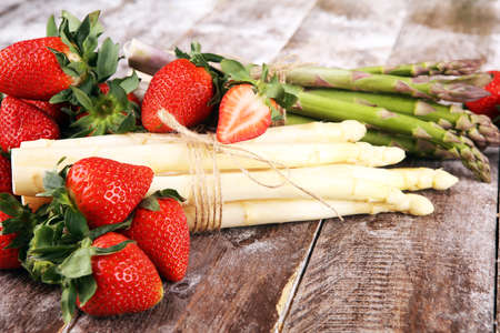 White and green fresh asparagus with a bunch of healthy strawberriesの写真素材