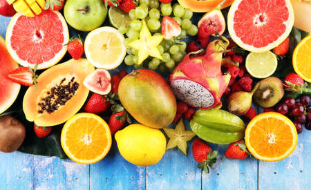 Tropical fruits background, many colorful ripe tropical fruits on wooden tableの写真素材