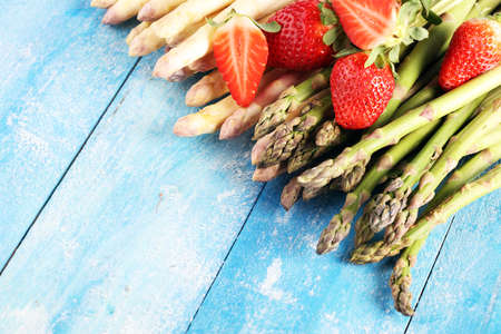White and green fresh asparagus with a bunch of healthy strawberriesの写真素材