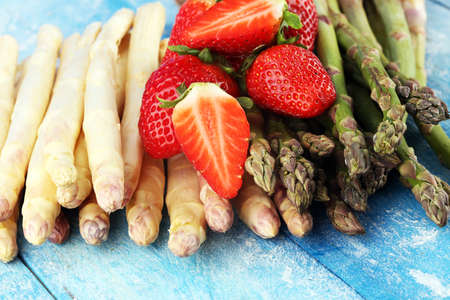 White and green fresh asparagus with a bunch of healthy strawberriesの写真素材