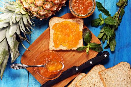 Toast bread with homemade pineapple jam or marmalade on rustic blue table served with butter for breakfast or brunchの写真素材