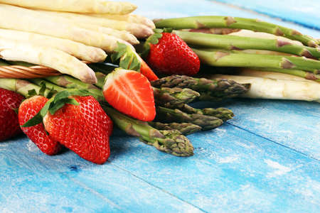 White and green fresh asparagus with a bunch of healthy strawberriesの写真素材