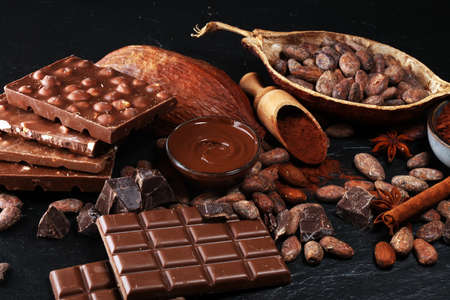 Melting chocolate or melted chocolate with a chocolate swirl and stack, chips and powder on dark tableの写真素材