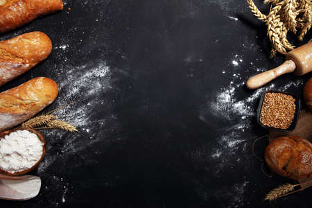 Assortment of baked bread and bread rolls on rustic table background.の写真素材