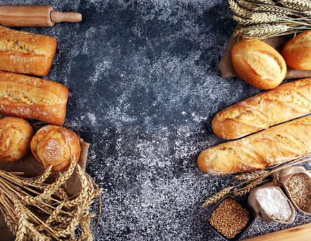 Assortment of baked bread and bread rolls on rustic table background.の写真素材