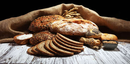 Assortment of baked bread and bread rolls on rustic table background.の写真素材