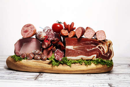cold meat assortment with delicious salami and herbs. Variety of meat products including proscuitto, jamon  and sausages on woodの写真素材