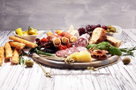 antipasto various appetizer. Cutting board with prosciutto, salami, coppa, cheese,bread sticks and olives on white woodenの写真素材