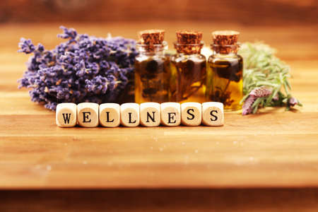 lavender oil in a glass bottle on a background of fresh flowers and Wellness sign with wooden cubesの写真素材
