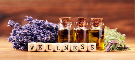 lavender oil in a glass bottle on a background of fresh flowers and Wellness sign with wooden cubesの写真素材