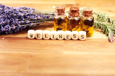 lavender oil in a glass bottle on a background of fresh flowers and Wellness sign with wooden cubesの写真素材