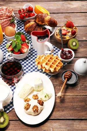 Huge healthy breakfast on table with coffee, orange juice, fruits, waffles and croissants. Cereals and balanced died. Good morning concept.の写真素材