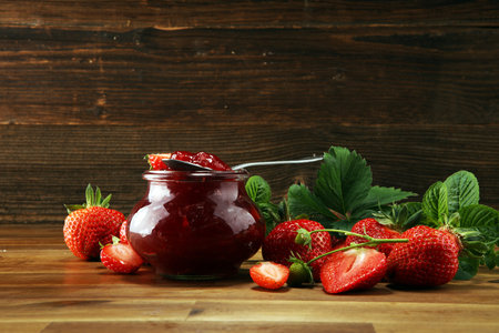 strawberry jam with fresh strawberries and mint. marmalade on spoon and jar on wood