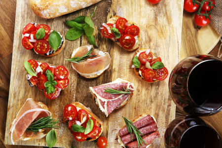 antipasto various appetizer. Cutting board with prosciutto, salami, coppa, cheese,bread sticks and olives on dark woodenの写真素材