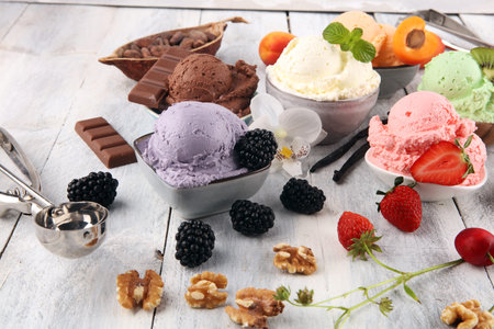 Set of ice cream scoops of different colors and flavours with berries, nuts and fruits decoration on white backgroundの写真素材