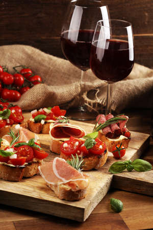 antipasto various appetizer. Cutting board with prosciutto, salami, coppa, cheese,bread sticks and olives on dark woodenの写真素材