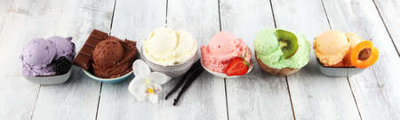 Set of ice cream scoops of different colors and flavors with berries, nuts and fruits decoration on white backgroundの写真素材