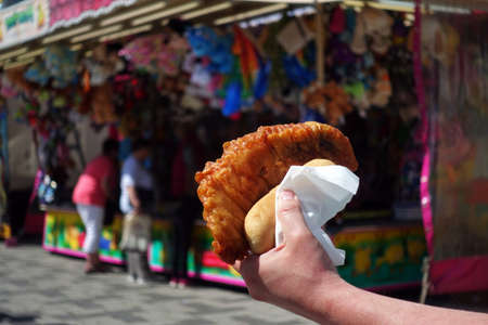 Traditional fish. Mobile food truck selling freshly hand buttered cod fish outdoors. Fish in hand at amusement park or street food festivalの写真素材
