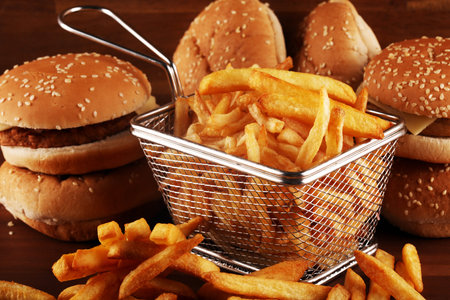 fresh tasty burger and french fries on wooden table. fast food bad for figure