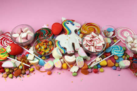 candies with jelly and sugar. colorful array of different childs sweets and treats on pink backgroundの写真素材