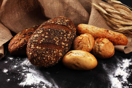 Assortment of baked bread and bread rolls on wooden table background. Bakery poster conceptの写真素材