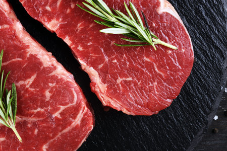 Steak raw. Barbecue Rib Eye Steak or rump steak on rustic table with rosemary