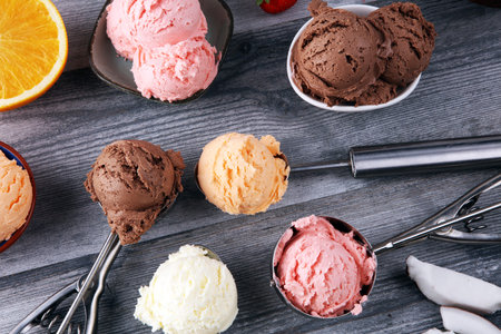 Set of ice cream scoops of different colors and flavours with berries, chocolate and fruits on table