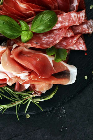 Marble cutting board with prosciutto, bacon, salami and sausages on wooden background. Meat platter appetizersの写真素材