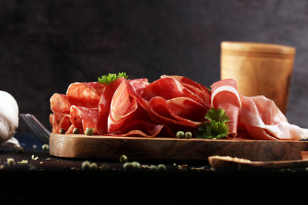 Food tray with delicious salami, coppa, crudo and herbs. Meat platter with selection on table