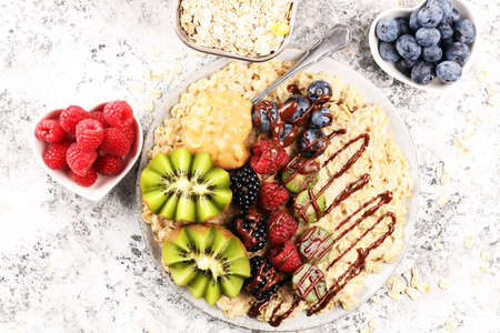 Bowl of oatmeal porridge with banana, raspberries, blueberries coconut and caramel sauce on rustic table, hot and healthy food for Breakfast.の写真素材