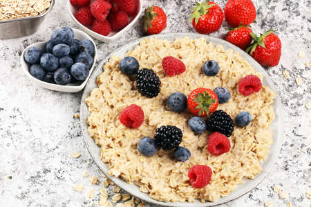 Bowl of oatmeal porridge with banana, raspberries, blueberries coconut and caramel sauce on rustic table, hot and healthy food for Breakfast.の写真素材