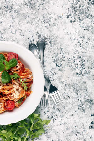tagliatelle pasta with tomato sauce parmesan basil on rustic tableの写真素材