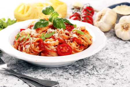 tagliatelle pasta with tomato sauce parmesan basil on rustic tableの写真素材