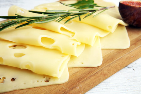cheese slices on wooden tray with parsley. cheese with whole