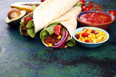 Mexican food, including tacos, guacamole, nachos and pepper on table
