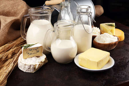 Different fresh dairy products on rustic background with milk, cheese, butter and cottageの写真素材