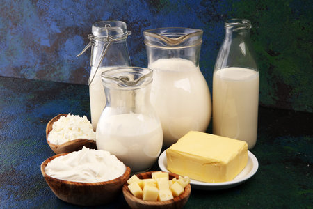 Different fresh dairy products on rustic background with milk, cheese, butter and cottageの写真素材