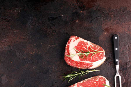 Raw fresh meat Ribeye Steak, seasoning and meat fork on a tableの写真素材