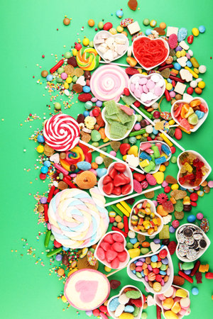 candies with jelly and sugar. colorful array of different childs sweets and treats on green