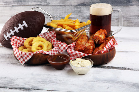 chicken wings, fries, beer and onion rings for football on a table. Great for Bowl football Gameの写真素材