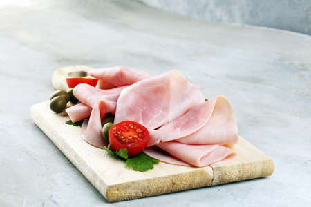 Sliced ham on wooden background. Fresh prosciutto. Pork ham sliced with rosemaryの写真素材