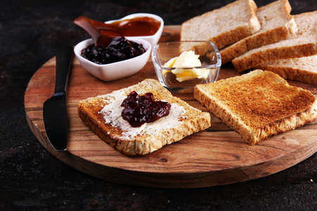 Toast bread with homemade strawberry jam and apricot marmalade on rustic table served with butter for breakfast or brunch.の写真素材
