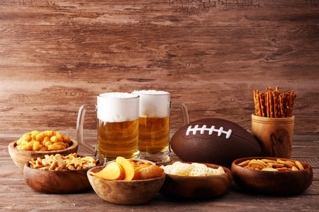Chips, salty snacks, football and Beer on a table. Great for Bowl Game projects.の写真素材