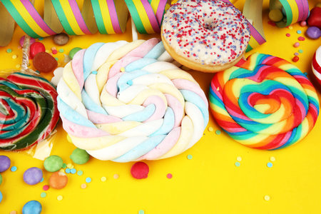 candies with jelly and sugar. colorful array of different childs sweets and treats on yellow